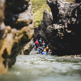 Group of people in wetsuits getting out the water surrounded by rocky cliffs in the Isle of Man